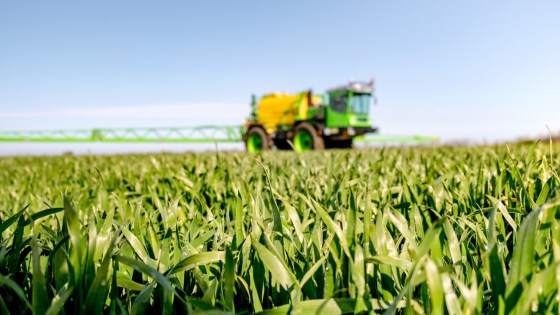 Moderne Pflanzenschutzspritze auf einem Acker mit grünem Getreidebestand unter blauem Himmel