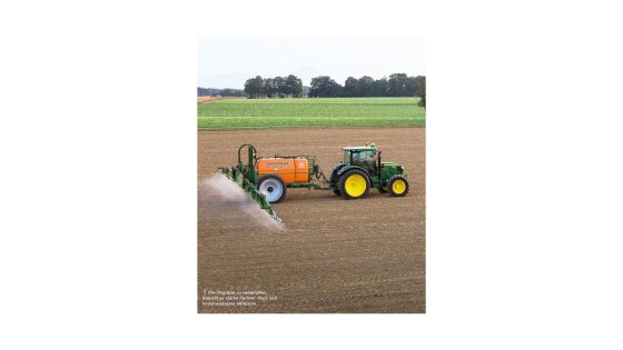 Traktor mit angebauter Pflanzenschutzspritze beim Ausbringen von Herbiziden zur Unkrautbekämpfung im Rapsanbau.